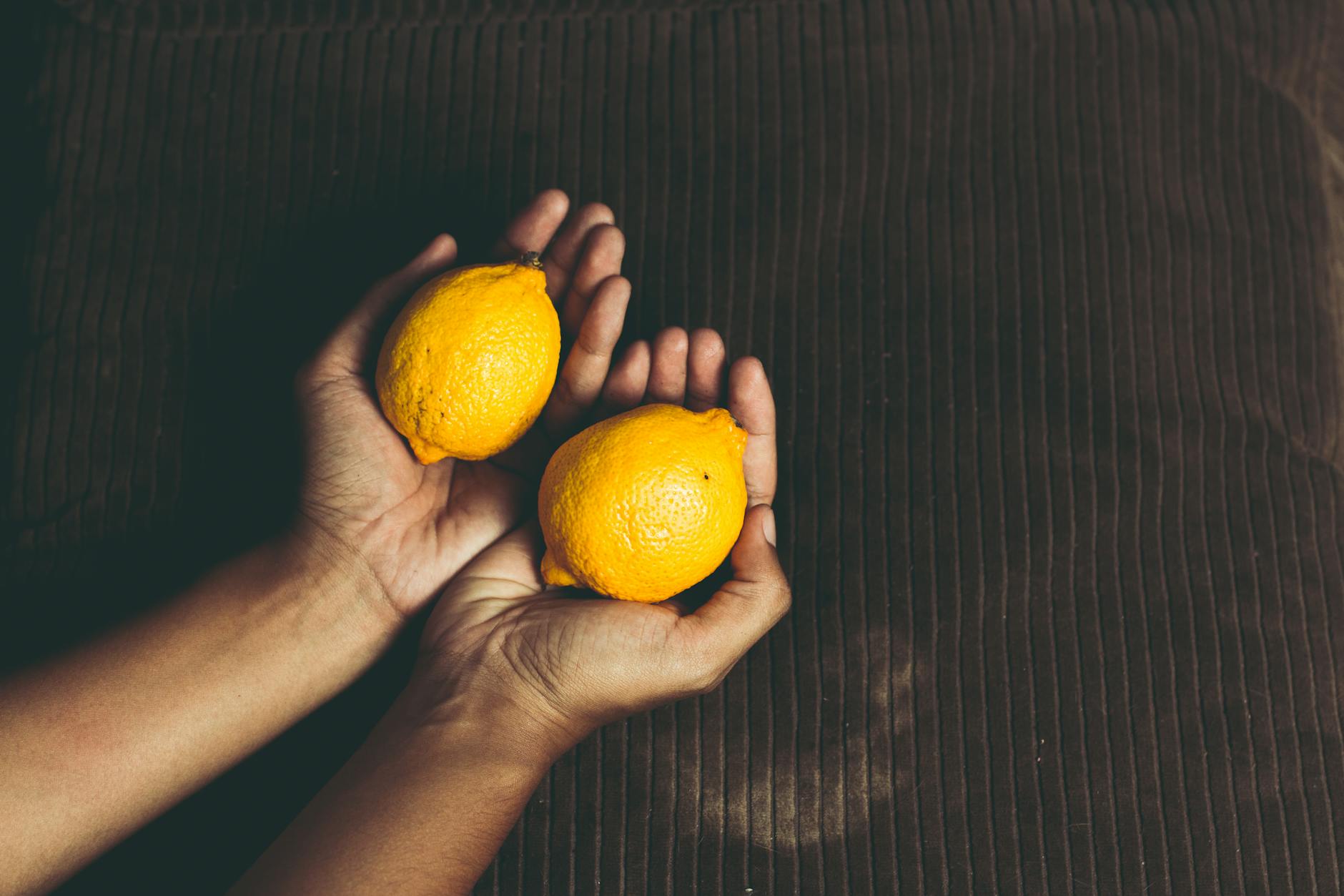 Cupped hands holding fresh lemons, symbolizing gentle care and self-nurturing.