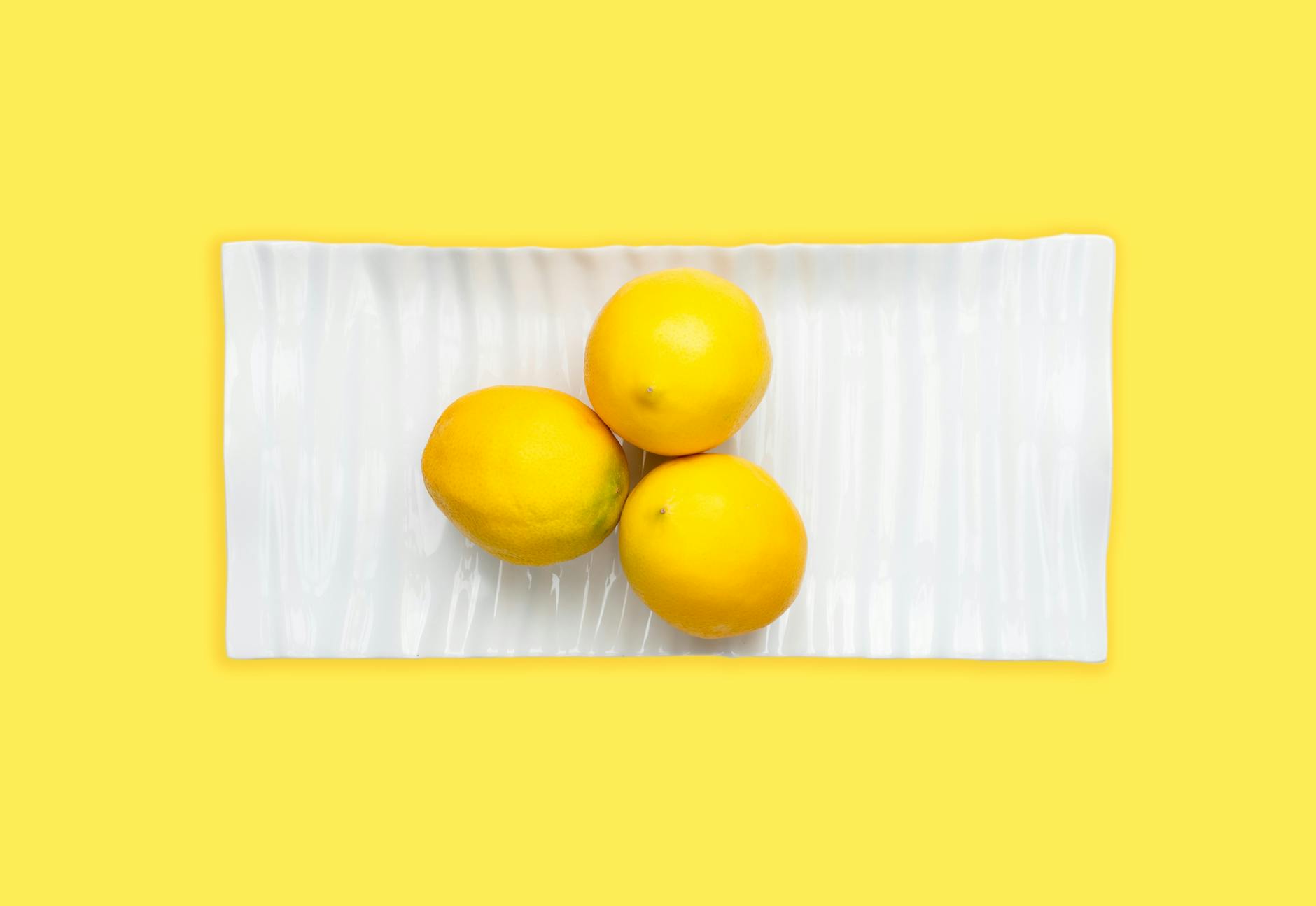 Bright yellow lemons on a pastel green background, representing slow, deliberate pleasure