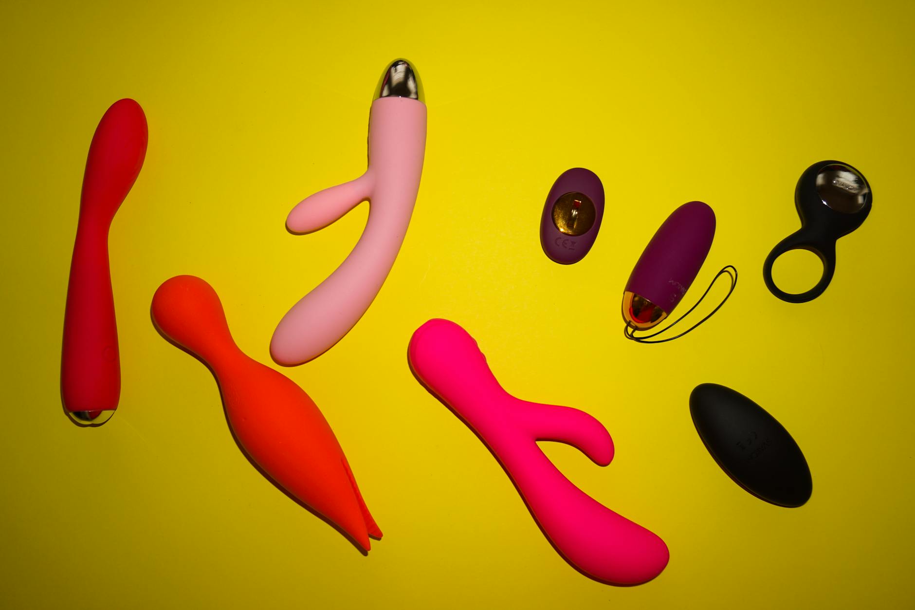 Vibrant collection of lemon and colorful clitoral vibrators arranged on a bright yellow surface