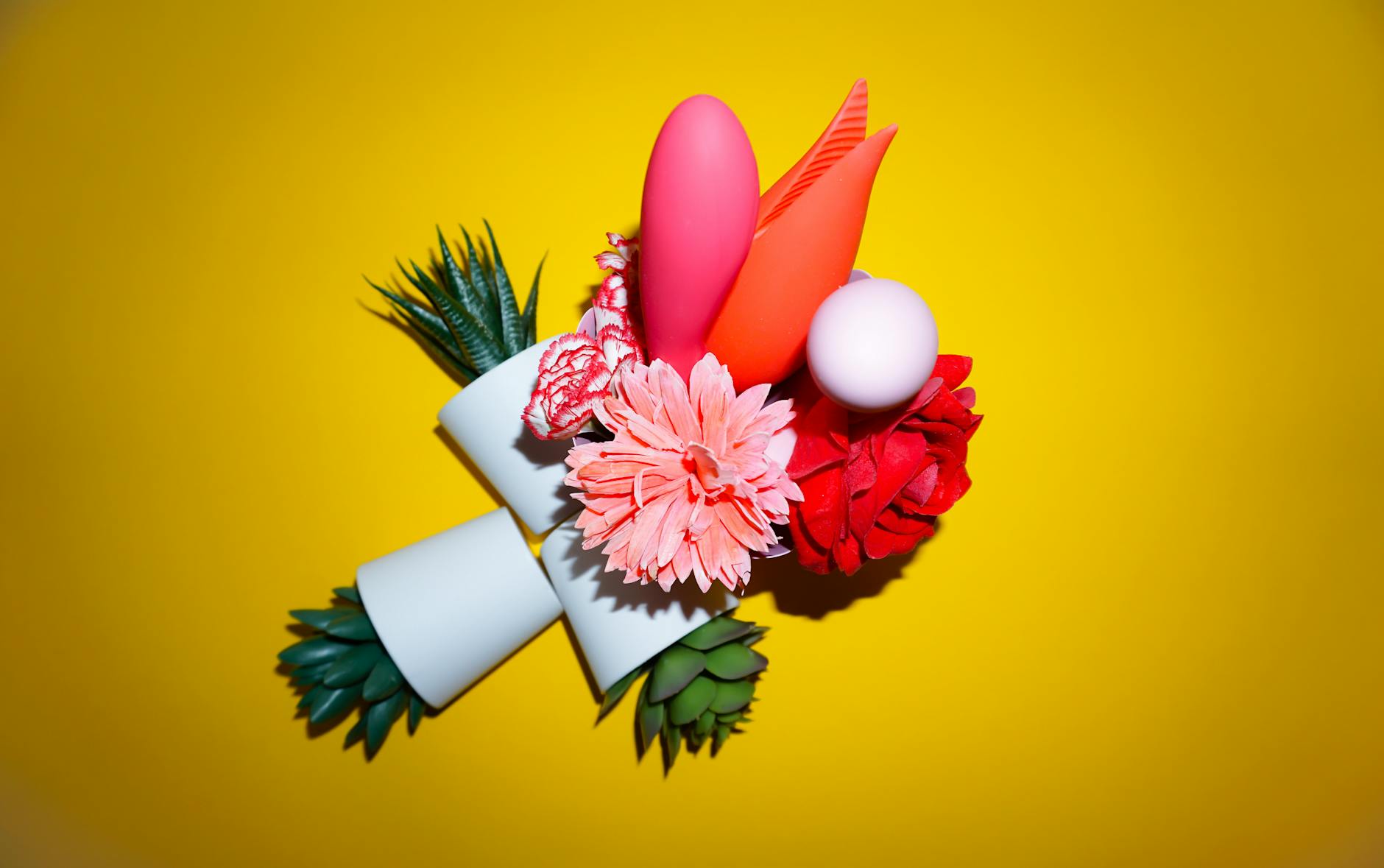 Vibrant colorful clitoral vibrators arranged on a bright yellow surface.